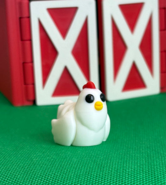 Toy chicken figurine with a red roof in front of red barn doors on a green surface